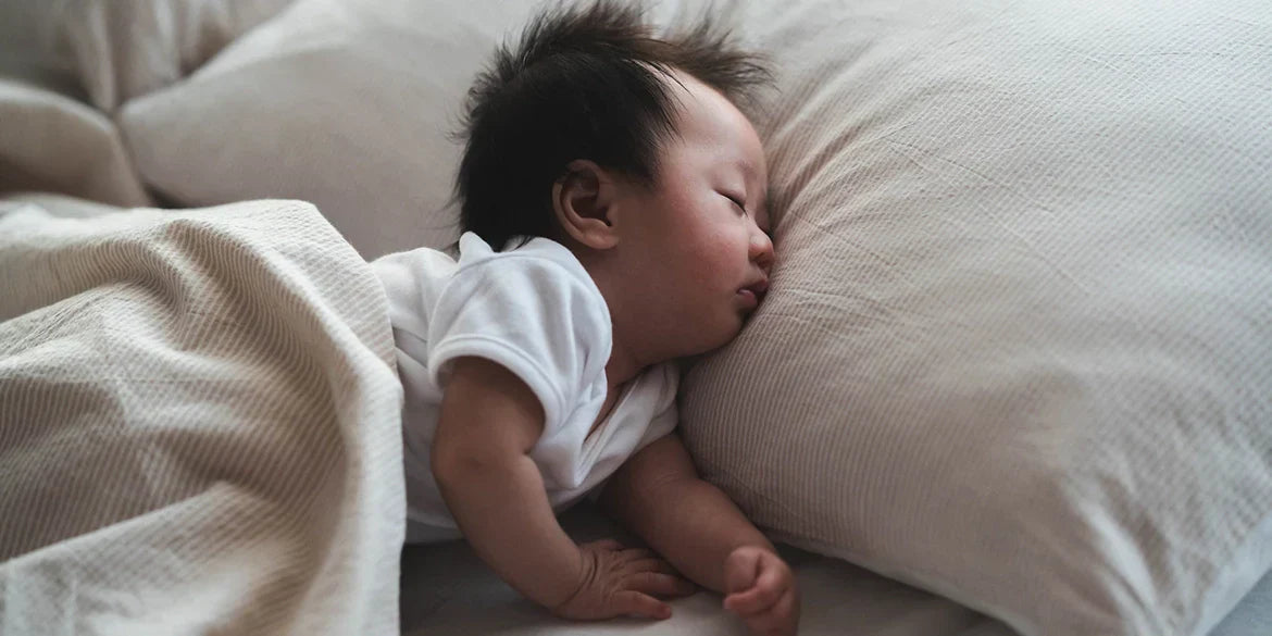 Baby schläft auf großem weißen Kissen mit weißer Decke