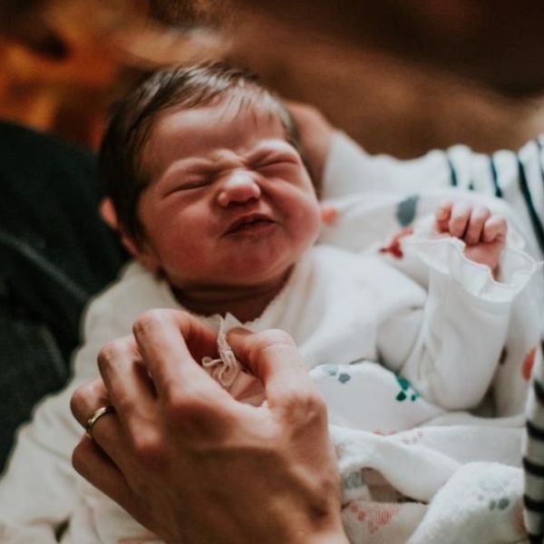 Schreiambulanz Baby liegt im Arm und rümpft die Nase