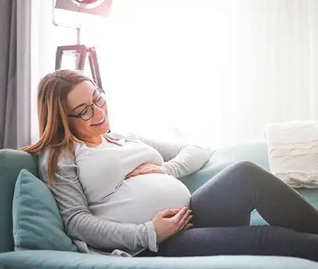 schwangere Frau glücklich auf einer Couch