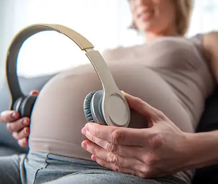 schwangere Frau hält Musik an ihren Bauch