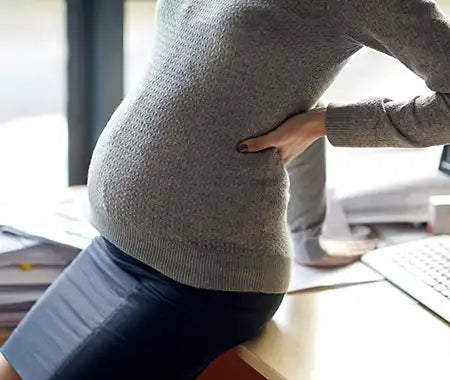 schwanger Frau im Büro auf Tisch sitzend