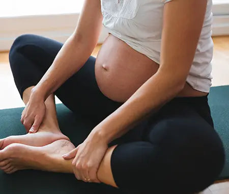 schwangere Frau auf Yogamatte sitzend